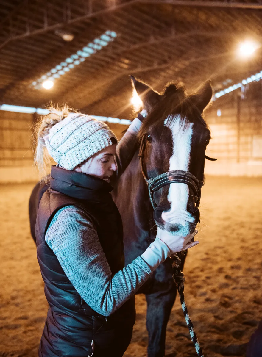 Erin Grace, equine massage therapist, performing bodywork on a horse at a barn near Ottawa